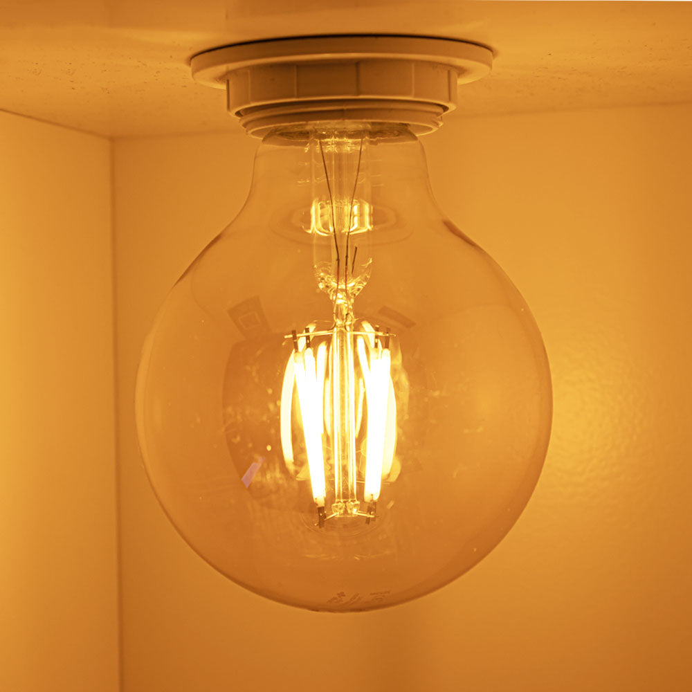 Nahaufnahme einer brennenden LED-Glühbirne mit warmem Schein, an der Decke montiert, Ansicht von unten.