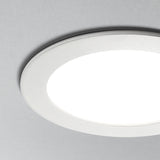 Nahaufnahme eines runden, weißen LED-Deckeneinbaustrahlers vor grauem Hintergrund, mit minimalistischem und modernem Design.