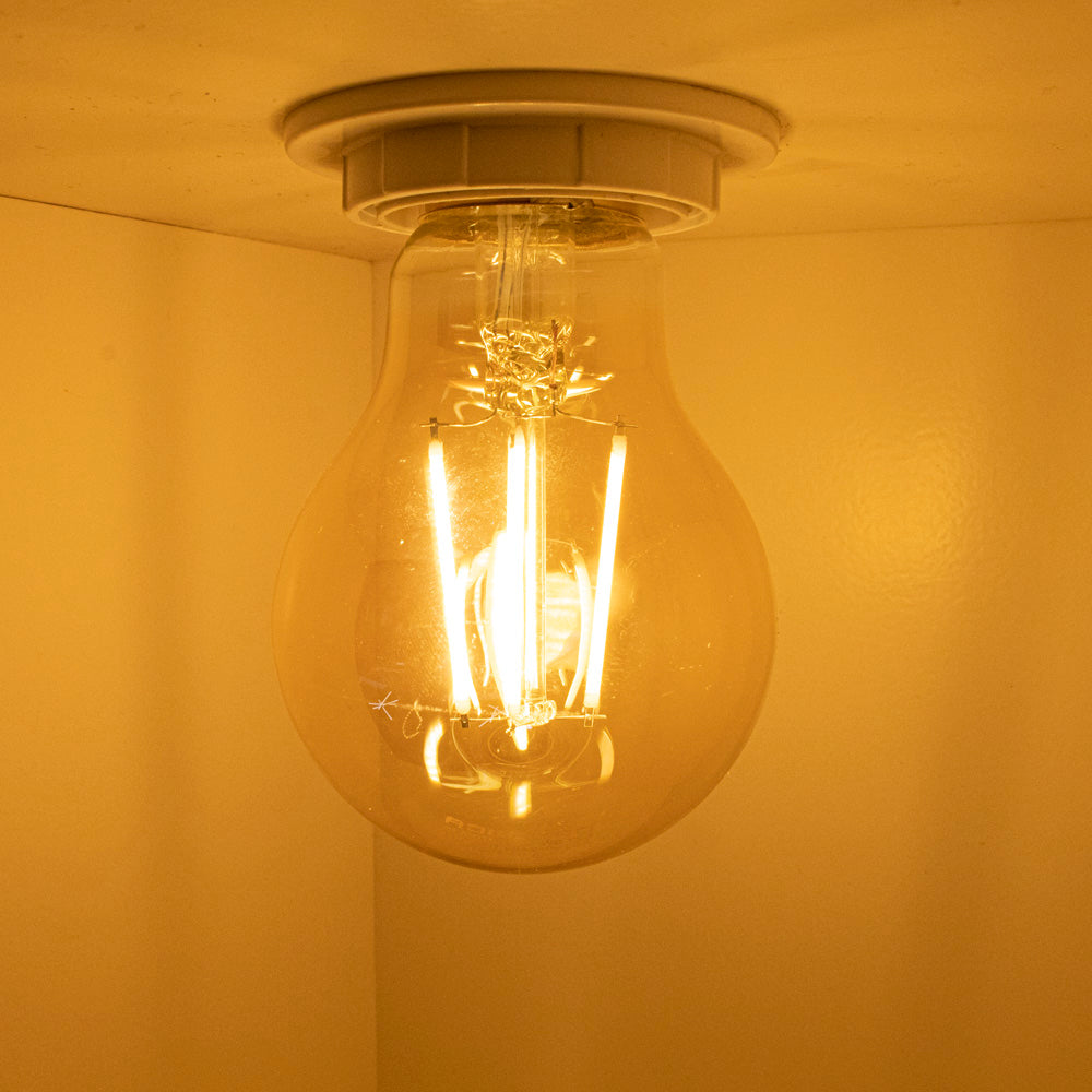 LED-Filamentlampe in warmweißer Farbtemperatur, montiert in einer Deckenleuchte, fotografiert von unten rechts.