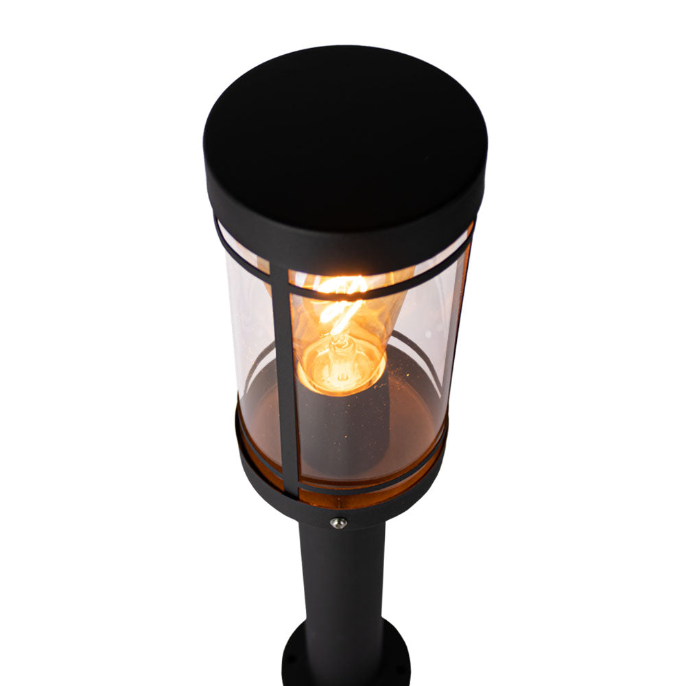 Schwarze moderne Außenleuchte mit rundem Schirm und transparentem Glas, von schräg oben betrachtet, mit sichtbar brennender Glühlampe im Inneren.