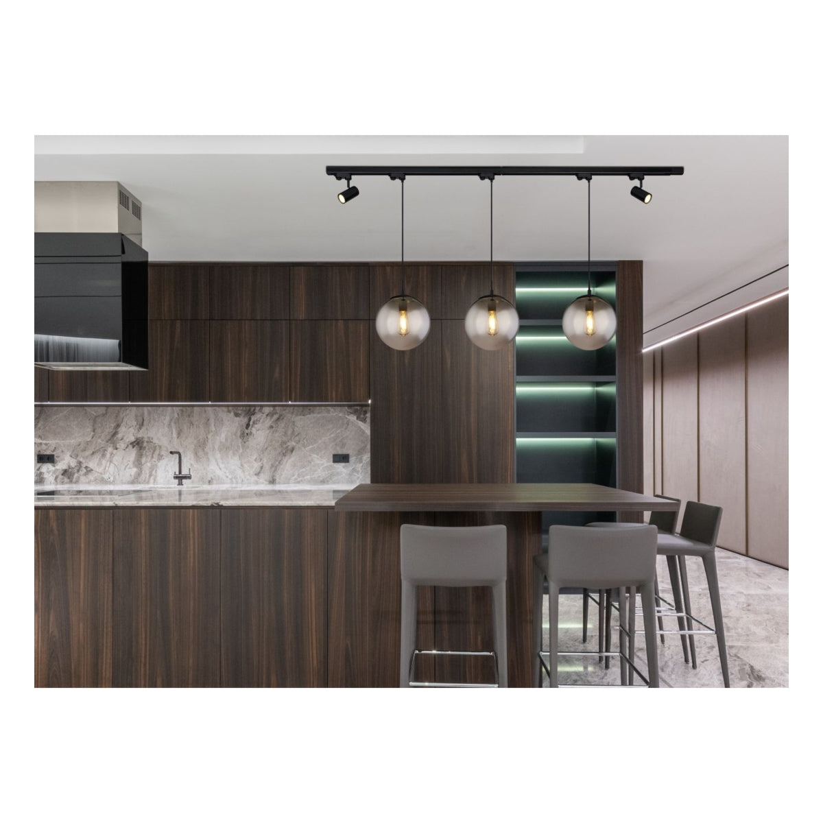 Eine moderne Pendelleuchte mit drei Rauchglaskugeln und einer schwarzen Schiene, montiert über einer Luxusküche mit dunklem Holzfurnier, einer Marmorarbeitsplatte und Barhockern – Frontalansicht.
