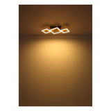 Moderne Deckenleuchte mit vier beleuchteten, sich überlappenden quadratischen Rahmen in warmweißem Licht, von unten an der Decke montiert, mit stimmungsvoller Lichtverteilung an der Wand.
