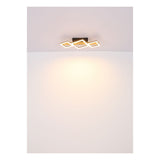 Moderne quadratische LED-Deckenleuchte im geometrischen Design, schwarzer Sockel mit warmweißem Licht, von unten betrachtet vor weißem Decken- und Wandhintergrund.
