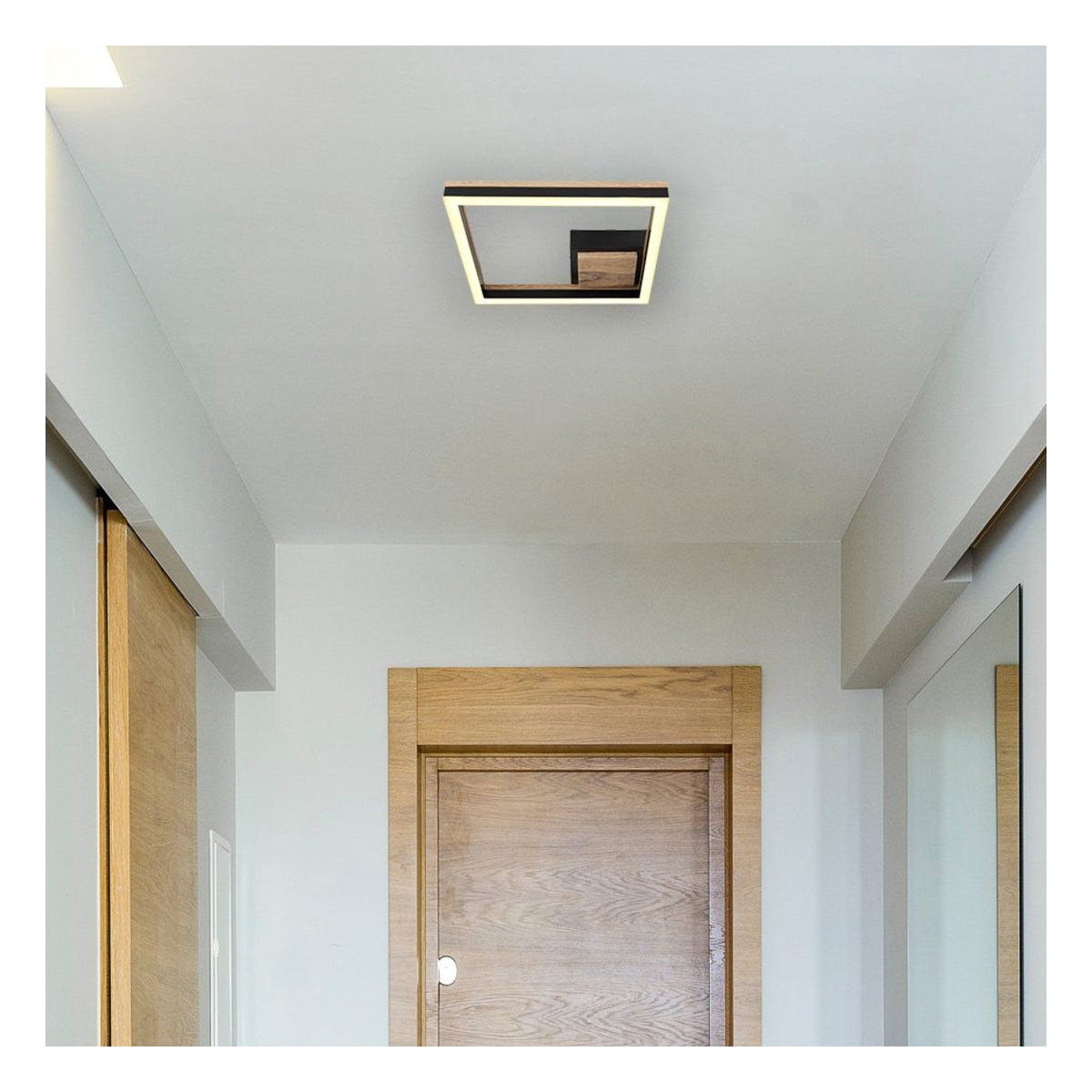Eine moderne quadratische Deckenleuchte mit Akzenten aus Holz und Schwarz, montiert an einer weißen Decke in einem Flur mit Holztüren und einem Spiegel – von unten betrachtet.