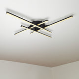 Moderne schwarze Deckenleuchte mit kreuzförmigem LED-Design, montiert an einer weißen Decke, fotografiert aus einer Untersichtsperspektive.