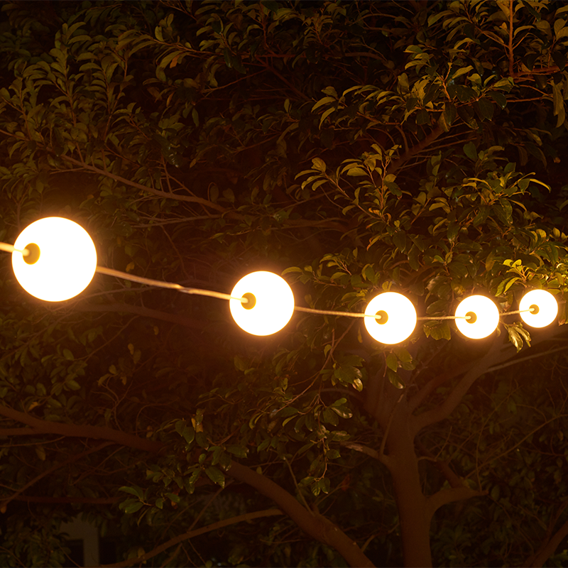 Stimmungsvolle LED-Lichterkette mit runden Kugeln, in einen Baum gehängt, Nachtansicht mit warmer Beleuchtung für den Außenbereich.