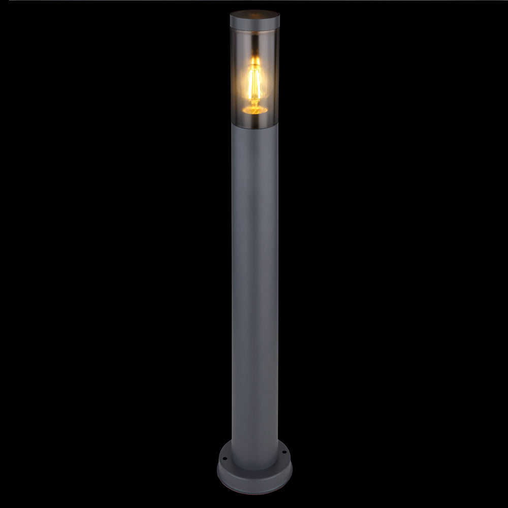 Moderne Außen-Stehleuchte in zylindrischer Bauform mit transparentem Schirm und sichtbarer Glühfaden-Lichtquelle, Frontalansicht vor schwarzem Hintergrund.