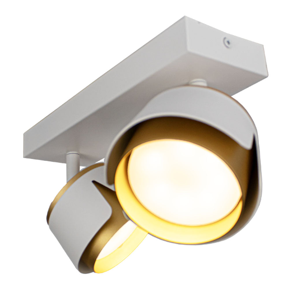 Moderner weißer Deckenstrahler mit zwei schwenkbaren Leuchtenköpfen und goldener Innenlackierung, der von schräg unten betrachtet für eine dynamische Optik sorgt.