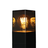 Nahaufnahme einer modernen schwarzen Außenlampe mit einer Retro-LED-Glühbirne in einem transparenten, quadratischen Gehäuse.