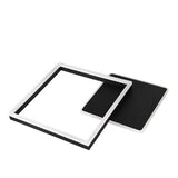 Moderne quadratische Wandleuchte im schwarz-weißen Design, von schräg oben betrachtet, mit minimalistischer offener Rahmenstruktur und integrierter LED-Beleuchtung.