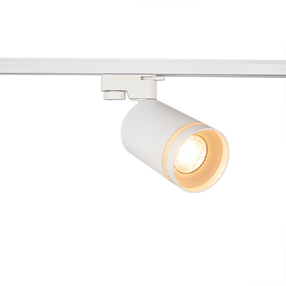 Weißer moderner LED-Schienenstrahler in zylindrischem Design, montiert auf einer weißen Schiene, abgewinkelte Frontansicht mit brennendem warmweißem Licht.