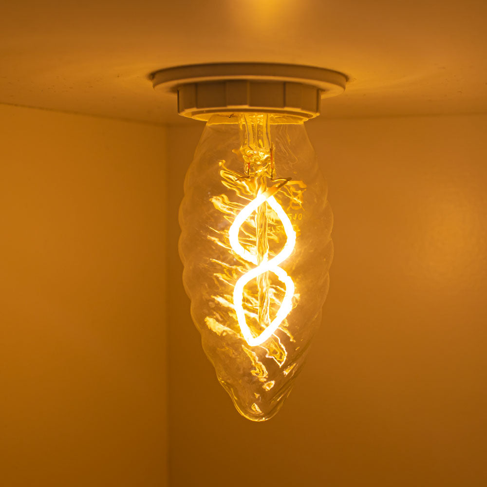 Dekorative spiralförmige LED-Glühbirne, an der Decke montiert und von unten fotografiert, mit warmweißem Licht und einem klaren, strukturierten Glasgehäuse.