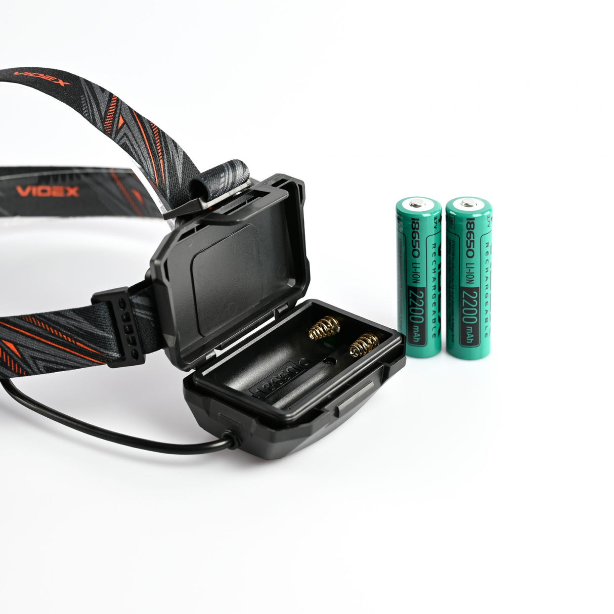 Nahaufnahme einer Videx-Stirnlampe mit offenem Batteriefach, einschließlich zwei wiederaufladbaren 18650-Li-Ionen-Akkus mit 2200 mAh, auf weißem Hintergrund.