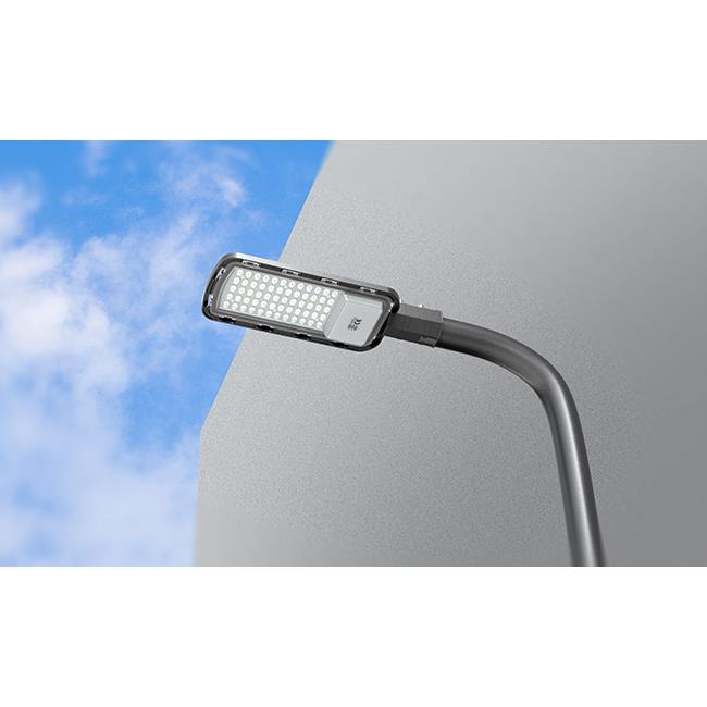 LED-Straßenlaterne von der Seite gesehen, montiert auf einem gebogenen Mast vor einem blauen Himmel mit Wolken, geeignet für energieeffiziente Außenbeleuchtung.