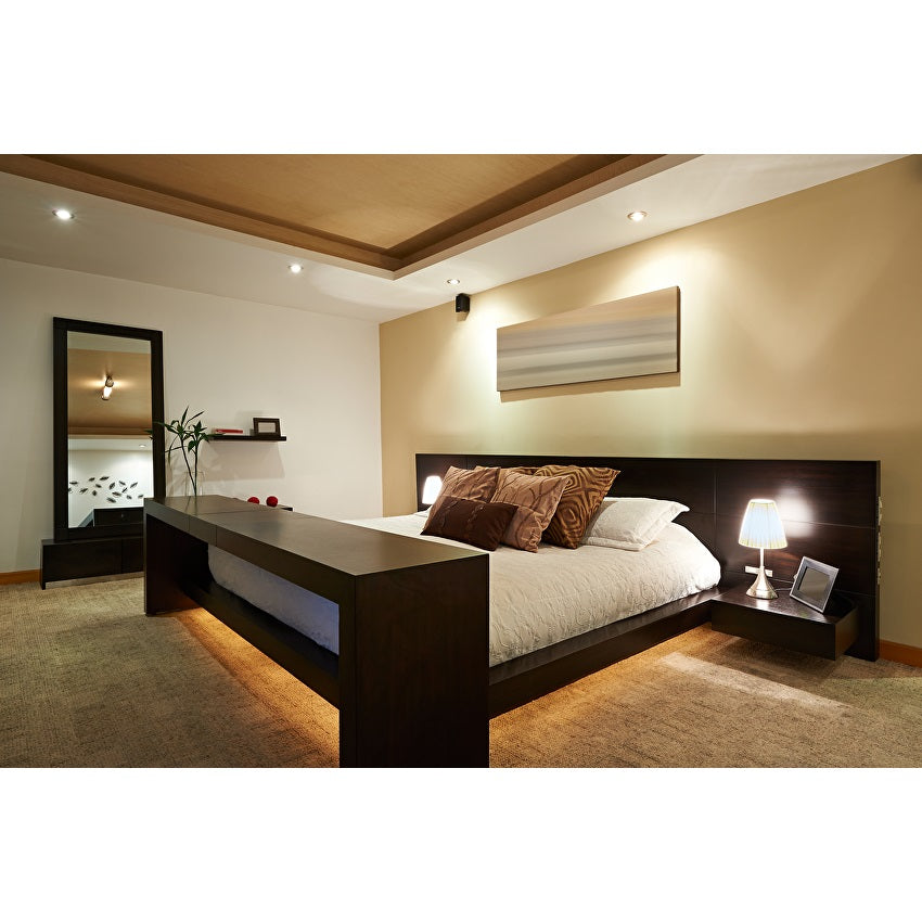 Modernes Schlafzimmer mit Doppelbett aus dunklem Holz, stimmungsvoller Beleuchtung und eingebauten Nachttischen, dargestellt in einer schrägen Frontansicht.