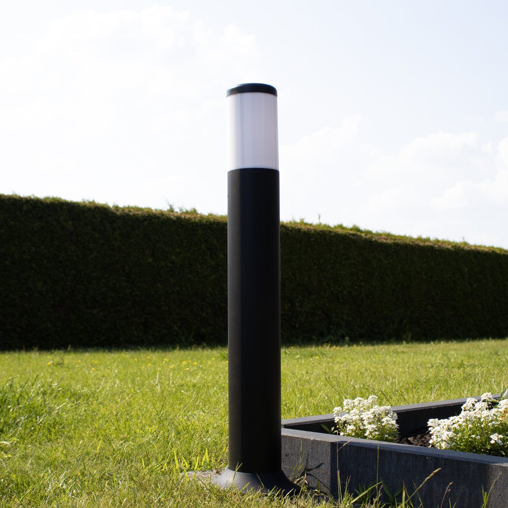 Schwarze moderne Außenleuchte ARVA, Standmodell im Garten, Nahaufnahme von der Seite mit einem erhöhten Pflanzgefäß und einem gepflegten Rasen.