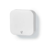 Weißes quadratisches Smart-Home-Sensorgerät mit abgerundeten Ecken, Seitenansicht, an einer weißen Wand montiert.