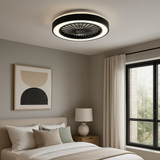 Ein moderner Deckenventilator mit integrierter LED-Beleuchtung im schwarz-weißen Design, montiert an der Decke eines stilvollen Schlafzimmers – Innenansicht von schräg unten.