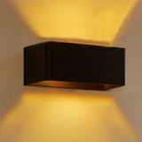 Moderne schwarze Wandleuchte mit indirekter LED-Beleuchtung, die warmweißes Licht nach oben und unten an eine cremefarbene Wand wirft – Seitenansicht.