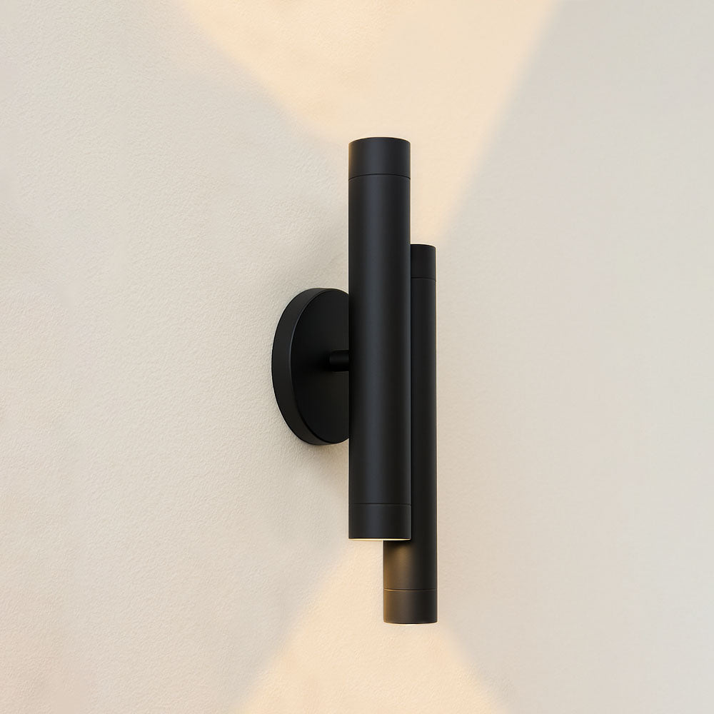 Moderne schwarze Wandleuchte mit zylindrischem Design an einer hellen Wand, Seitenansicht mit nach oben und unten gerichteten Lichtstrahlen.