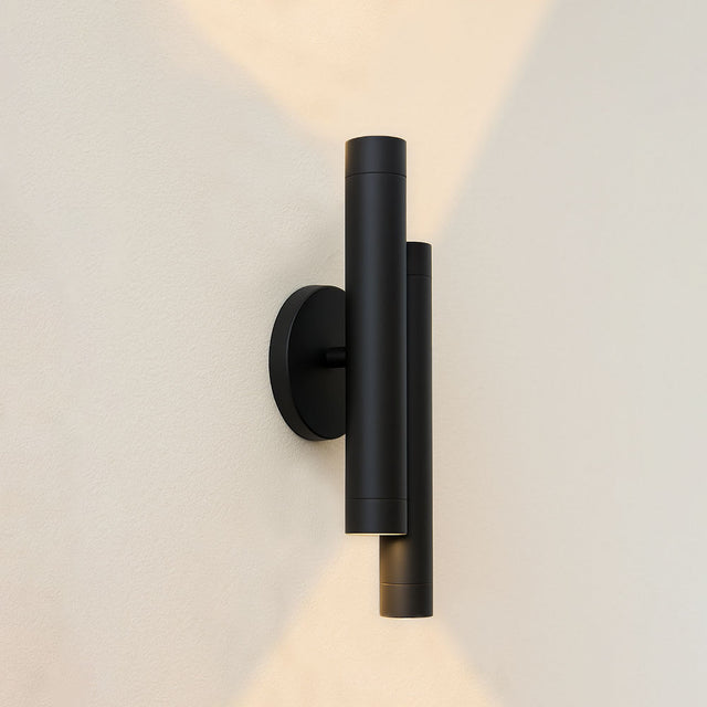 Moderne schwarze Wandleuchte mit zylindrischem Design an einer hellen Wand, Seitenansicht mit nach oben und unten gerichteten Lichtstrahlen.