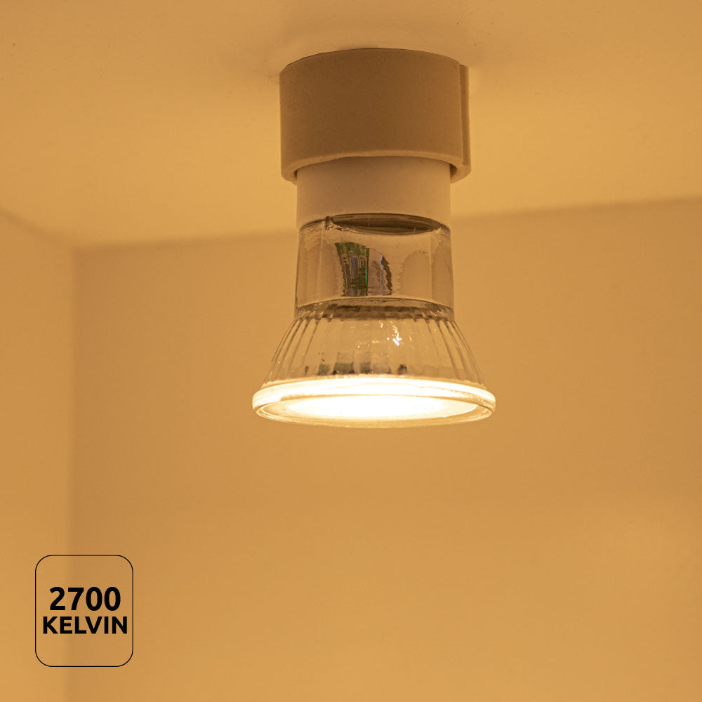 Blick nach oben auf einen Deckenstrahler mit warmweißem Licht (2700 Kelvin), montiert in einer weißen Fassung, das vor einem beigen Hintergrund strahlt – ideal für stimmungsvolle Beleuchtung im Wohnbereich.