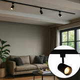 Schwarzer moderner Schienenstrahler Lighting LED – Nahaufnahme eines schwarzen Schienenstrahlers, der an einer Deckenschiene in einem geschmackvoll eingerichteten Wohnzimmer mit natürlichem Licht montiert ist.