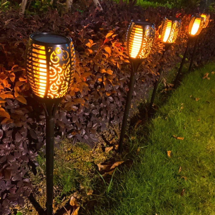 Dekorative Solar-Gartenleuchten mit Flammeneffekt, platziert entlang eines Gartenweges mit seitlichem Blick in die Abendbeleuchtung.