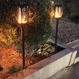 Dekorative Solar-Gartenfackeln mit Flammeneffekt, in der Dämmerung entlang eines Gartenweges platziert, von vorne mit leuchtenden Mustern und warmer Stimmungsbeleuchtung.