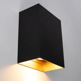 Moderne schwarze Wandleuchte mit goldfarbenem Innenleben, schräg von unten fotografiert mit Blick auf den nach unten gerichteten Lichtstrahl.