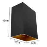 Schwarze rechteckige Wandleuchte mit goldener Innenseite, Maße 13 cm hoch, 10 cm breit und 6 cm tief, abgewinkelte Vorderansicht.