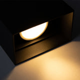 Nahaufnahme einer modernen schwarzen Wandleuchte mit warmweißem LED-Licht, das nach unten gerichtet ist und für eine stimmungsvolle Beleuchtung sorgt.