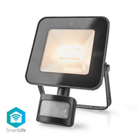 Schwarzer SmartLife LED-Außenstrahler mit Bewegungsmelder, schräge Frontansicht, eingeschaltet mit warmweißem Licht.