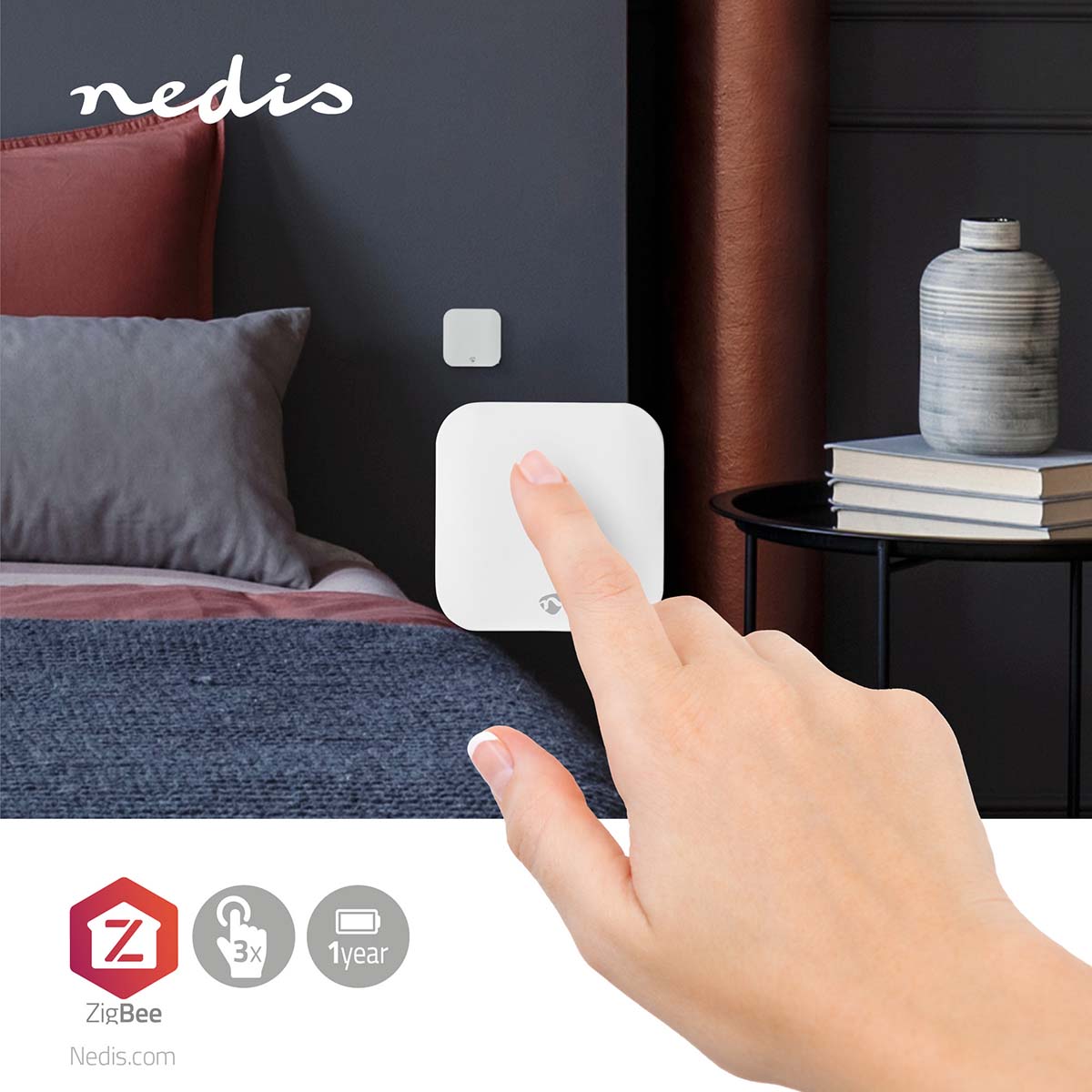 Nahaufnahme einer Hand, die einen weißen intelligenten drahtlosen ZigBee-Wandschalter von Nedis bedient, der an der Wand neben einem modernen Bett in einem stilvoll eingerichteten Schlafzimmer montiert ist – Vorderansicht mit Fokus auf die Produktverwendung.